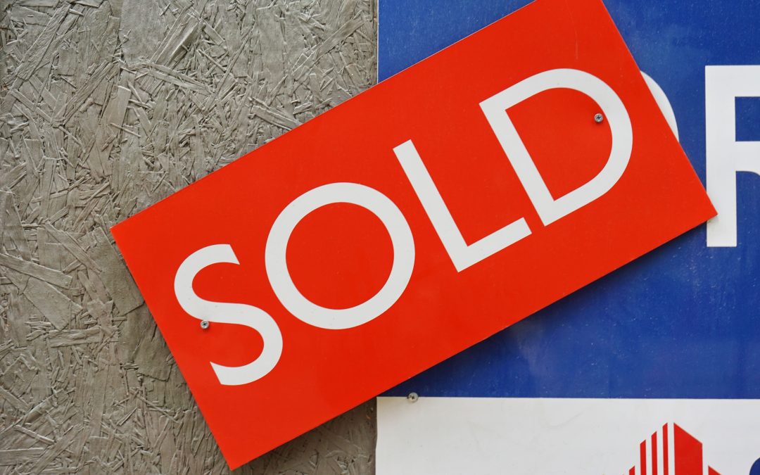 Red sold sign attached to a real estate sign