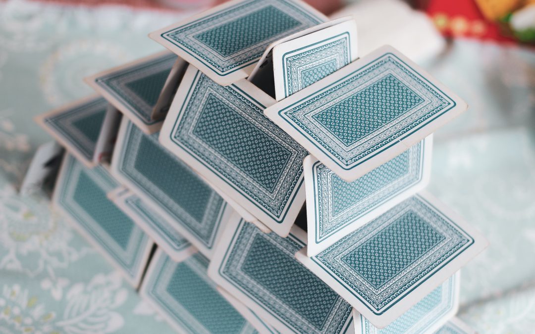 Photo of a house of cards. The cards are light blue.