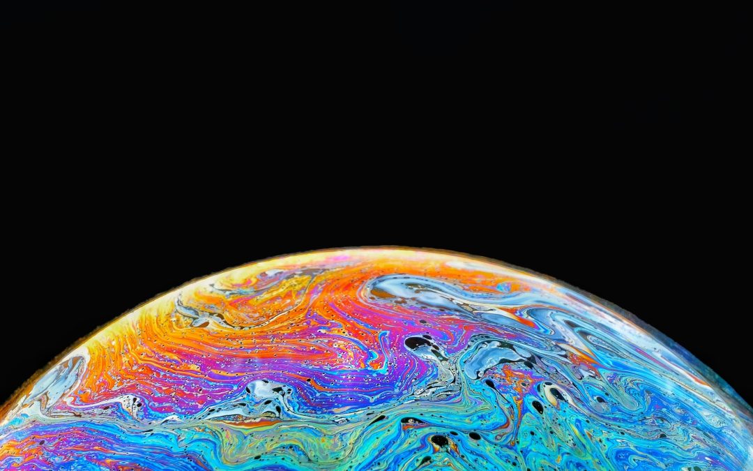 Close up of the surface of a bubble showing colours swirling on the surface, the background is black.